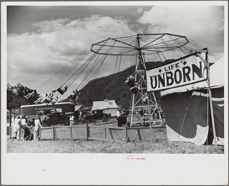 A ride at a fair with a tent saying "Life's Unborn"